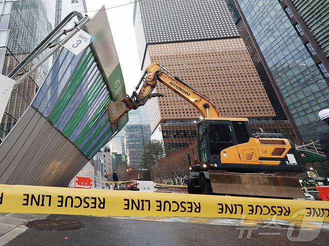 눈이 내리고 바람이 강하게 분 27일 오후 서울 종로구 KT 광화문 사옥 리모델링 현장에서 굴삭기가 강풍에 쓰러져 기울어진 공사장 가림막을 받치고 있다. 2025.1.27/뉴스1 ⓒ News1 황기선 기자