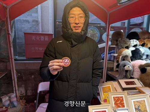 치엔먼 묘회에 참여한 상인 장캉이 공예품을 들어보이고 있다.