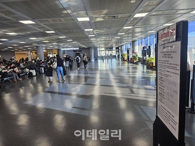 지난 29일 부산 김해공항의 탑승장 앞에 항공사가 지연 운행을 알리는 안내문을 붙힌 가운데 승객들이 탑승을 기다리고 있다. (사진=김형환 기자)
