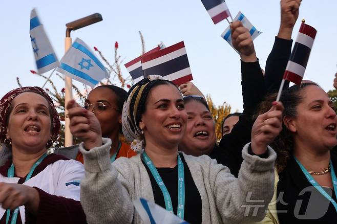 30일(현지시간) 새로 석방된 태국 인질 5명을 이송하는 구급차가 도착하자 비어 야코브의 샤미르 의료 센터 앞에 모인 의료진들이 이스라엘 국기와 태국 국기를 흔들고 있다. ⓒ AFP=뉴스1 ⓒ News1 류정민 특파원