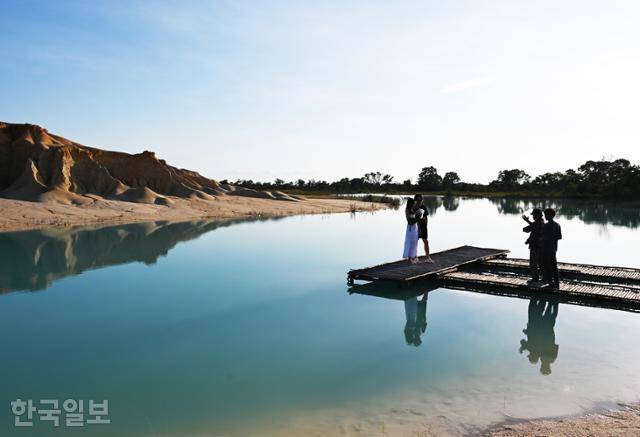 여행객이 빈탄 소금사막의 푸른 호수를 배경으로 사진을 찍고 있다.