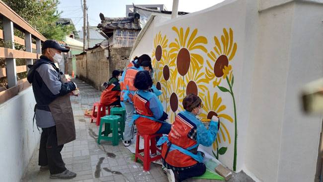 2023년 대구종합사회복지관의 벽화사업에 참여한 대구민들레봉사단이 벽에 그림을 그리는 모습. 초록우산 제공