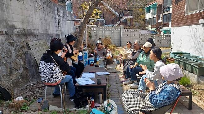 서울 강북구에 거주하는 이보라씨는 집앞 20평 남짓한 텃밭에서 계절별 푸성귀와 허브 등 다양한 채소를 기르고 있다. 지난해 봄, 마을 사람들과 함께 진달래 화전을 만든 뒤 텃밭에 모여 우쿨렐레 공연을 즐기고 있는 모습. 이보라씨 제공.