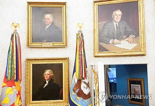 백악관 집무실에서 복도 방향을 바라보고 찍은 사진. 전직 미국 대통령들의 초상화와 도널드 트럼프 대통령의 머그샷이 한 프레임 안에 들어간다. [로이터=연합뉴스]