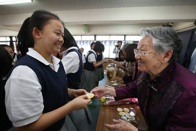 일본군 ‘위안부’ 피해자 길원옥 할머니가 2013년 5월24일 일본 히가시오사카조선중급학교를 찾아 학생들에게 길 할머니와 김복동 할머니의 캐리커쳐가 그려진 버튼을 선물하고 있다. 이날 하시모토 도루 오사카 시장과의 면담을 거부한 할머니들은 면담 일정 대신 이 학교를 찾아 차별을 견디며 공부하는 학생들을 격려했다. 오사카/이정아 기자 leej@hani.co.kr
