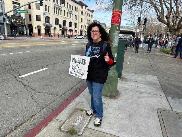 미국인 엘레나 모레티가 17일 미 캘리포니아주 오클랜드 시내에서 '머스크가 불법 점거 중이다. 지금 당장 제거하라'라고 적힌 팻말을 들고 있다. 민주당 지지자인 모레티는