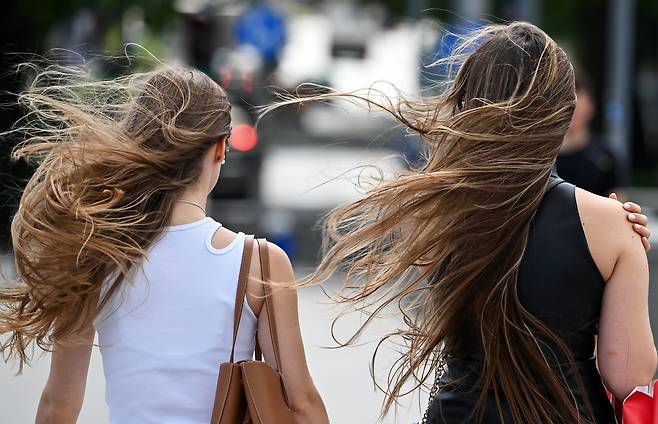 Two women walk across the street as the wind blows through their hair.  (Getty Images)