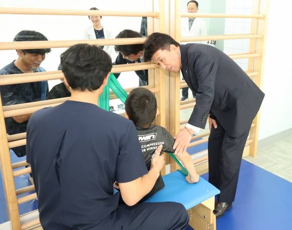 함영주 하나금융지주 회장(맨 오른쪽)이 17일 서울 마포구 푸르메재단 넥슨어린이재활병원에서 ‘장애 아동ㆍ청소년을 위한 재활 및 학습 보조기구 전달식’에 참석해 중추신경계 발달치료를 받고 있는 장애 아동에게 격려의 말을 전하고 있다. 하나금융지주 제공.