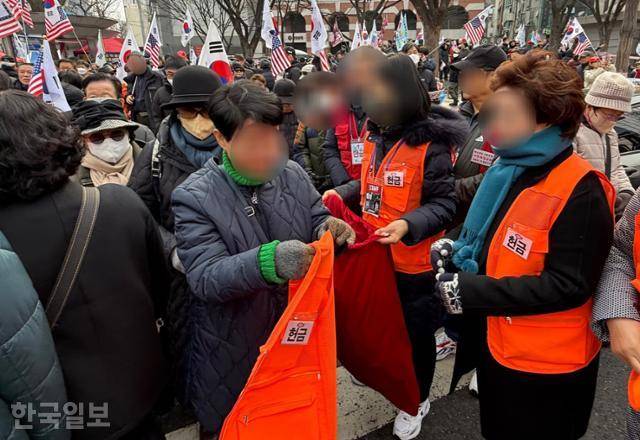 윤석열 대통령 탄핵반대 국민대회가 15일 서울 광화문 사거리 일대에서 열린 가운데 봉사자들이 헌금 주머니와 조끼를 챙기고 있다. 이들 대부분은 자유마을, 대한민국바로세우기국민운동본부 소속 회원들이다. 문지수 기자