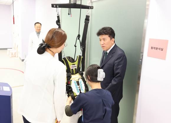 지난 17일 함영주(맨 오른쪽) 하나금융지주 회장이 서울 마포구 푸르메재단 넥슨어린이재활병원에서 열린 ‘장애 아동·청소년을 위한 재활 및 학습 보조기구 전달식’에 참석해 중추신경계 발달치료를 받는 장애 아동에게 격려의 말을 전하고 있다.  하나금융지주 제공