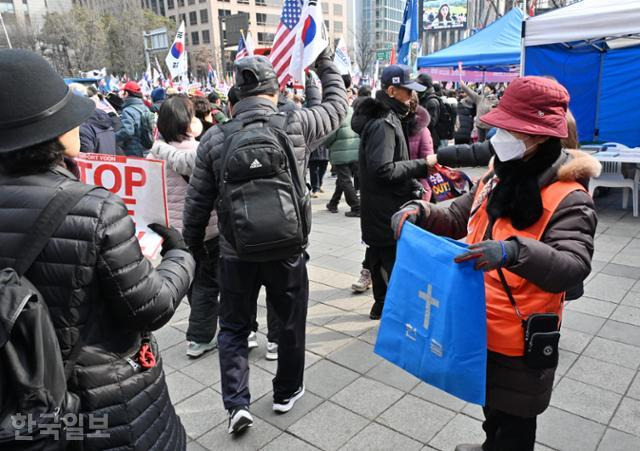 윤석열 대통령 탄핵 반대 국민대회가 15일 서울 광화문 사거리 일대에서 열린 가운데 주황색 조끼를 입은 봉사자가 헌금 봉투를 들고 있다. 홍인기 기자