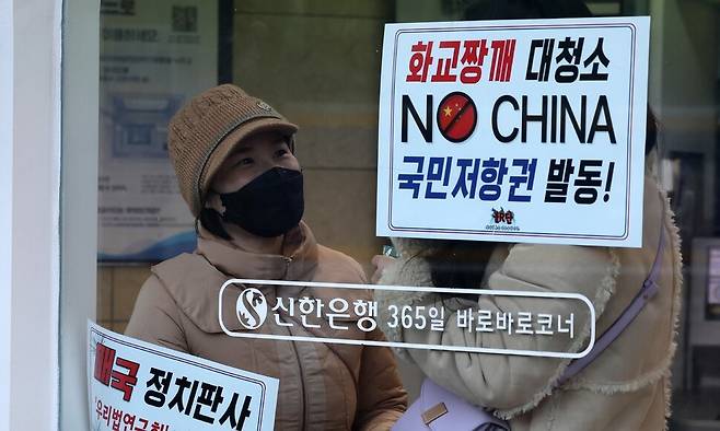 윤석열 대통령 탄핵심판 10차 변론기일이 지난 20일 오후 서울 종로구 헌법재판소 대심판정에서 열려 인근에서 탄핵 반대 단체의 집회에 참여한 시민들이 손팻말을 은행 유리창에 갖다댄 채 대화하고 있다. 김영원 기자 forever@hani.co.kr