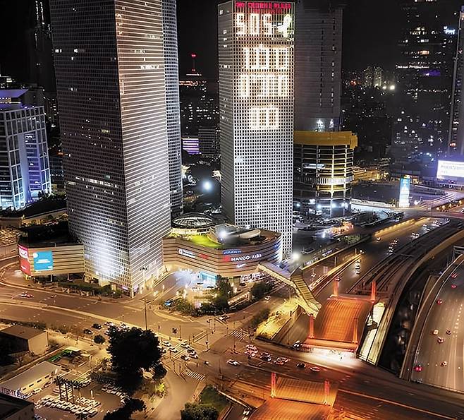 이스라엘 기차역에도 추모의 불빛 - 22일 오후 이스라엘 텔아비브 하샬롬 기차역(사진 아래쪽) 일대가 주황색 조명으로 빛나고 있다. 하마스에 납치됐다가 시신으로 돌아온 두 어린아이의 머리칼 색을 본뜬 것이다. 위쪽 빌딩의 문구 중 첫 줄 ‘505’는 전쟁 발발 505일째라는 의미, 그 아래 히브리어는 “우리는 당신을 기다리고 있다”는 의미다. /X