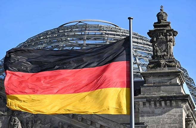 24일(현지시간) 독일 베를린 국회의사당(독일 하원)이 있는 라이히슈타크 건물의 큐폴라 앞에 독일 국기가 바람에 펄럭이고 있다. [AFP]