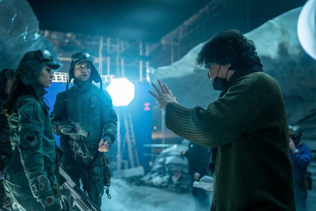 영화 ‘미키 17’의 촬영장에서 봉준호 감독(오른쪽)이 카이(아나마리아 바토로메이)와 익스펜더블 미키(로버트 패틴슨)에게 장면에 대한 설명을 하고 있다. 사진제공=Warner Bros.