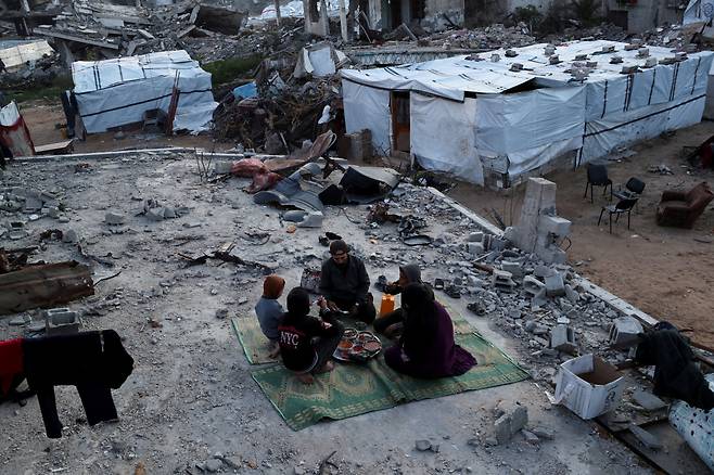 지붕도 벽도 없는 집에서…금식 후 첫 식사 2일(현지시간) 가자지구 북부 자발리야 난민캠프에서 라마단 금식을 마친 팔레스타인인 가족이 파괴된 집 잔해 위에서 식사하고 있다. 로이터연합뉴스