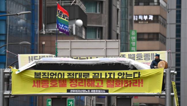 4일 오전 서울 중구 지하철 명동역 1번 출구 앞 지하차도 진입 차단 시설 위에서 세종호텔 노조 관계자가 정리해고 철회 등을 요구하며 고공농성을 벌이고있다. 백동현 기자