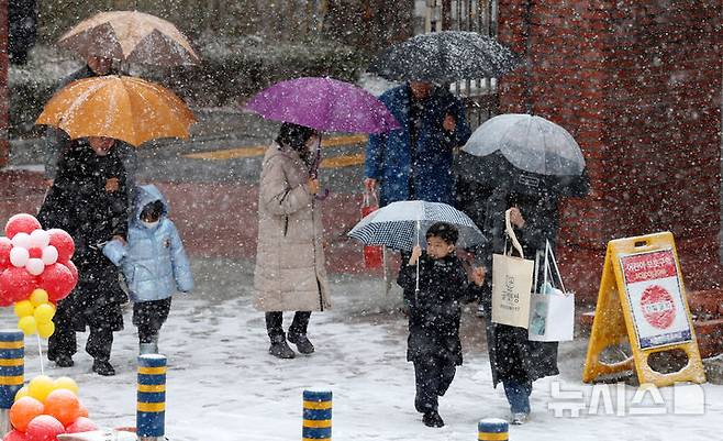 [서울=뉴시스] 추상철 기자 = 눈이 내린 4일 오전 서울 마포구 아현초등학교에서 열린 100주년 입학식에서 학부모와 신입생이 입학식장으로 향하고 있다. 2025.03.04. scchoo@newsis.com