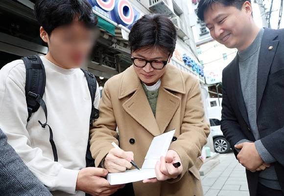 한동훈 전 국민의힘 대표가 지난 2일 공개 행보를 시작하며 책을 들고 찾아온 지지자에게 사인을 해주고 있다. [사진=연합뉴스]