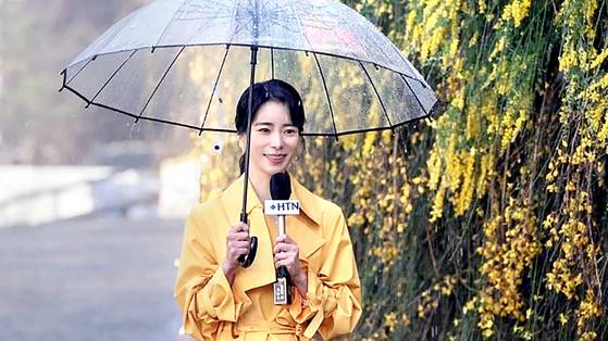 A scene from Netflix hit ″The Glory″ (2022-2023) shows its main antagonist Park Yeon-jin, played by Lim Ji-yeon, delivering the weather news in a rain coat. [SCREEN CAPTURE]