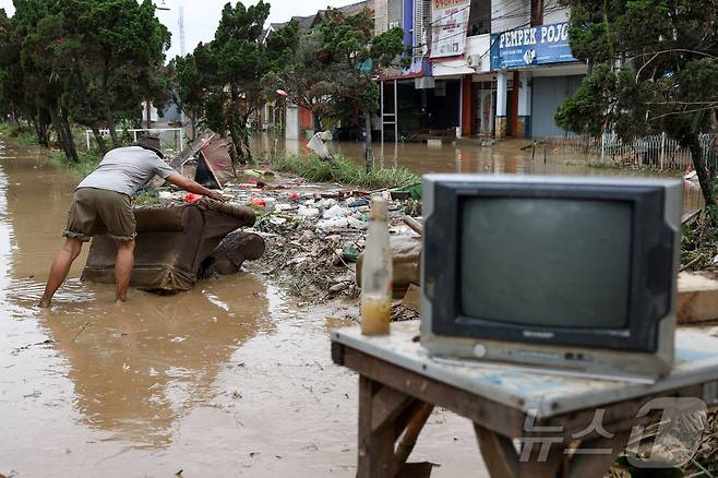 4일(현지시간) 인도네시아 자카르타 외곽 베카시에서 폭우가 내린 후 홍수가 주택가를 덮치자 한 남성이 가재도구를 건지고 있다. 2025.3.6 ⓒ 로이터=뉴스1