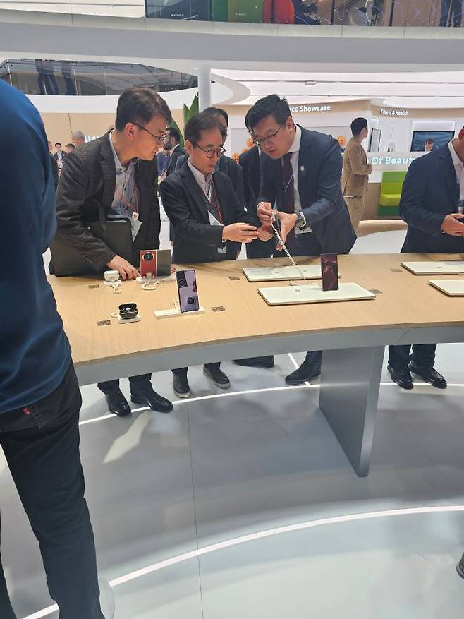 장덕현 삼성전기 사장이 5일(현지시간) MWC 2025 전시장을 찾은 모습. 스마트폰 후면 카메라 부분을 살펴보고 있다.ⓒ임채현 기자