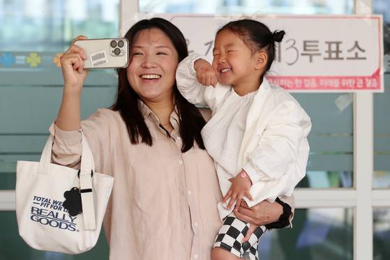 A mother poses for a selfie with her daughter, showing off the ballot stamp on the back of her hand after voting at a polling station in Dalseong County, Daegu, Wednesday. [NEWS1]