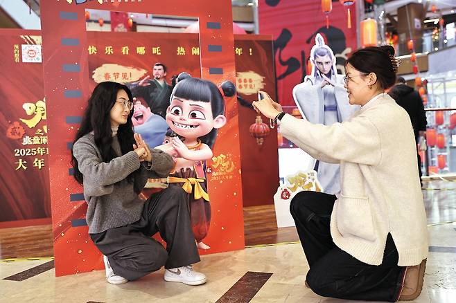 지난달 12일 중국 랴오닝성 선양에서 열린 문화 행사에서 한 여성이 중국 애니메이션 ‘너자2′의 캐릭터 앞에서 똑같은 자세를 취하며 사진을 찍고 있다. 뛰어난 애니메이션 기술과 애국심을 자극하는 서사를 적절히 버무렸다는 평가 속에 이 작품은 중국인들로부터 선풍적인 인기를 끌고 있다./게티이미지코리아