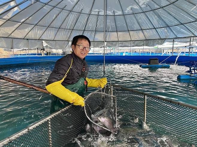 충청남도 금산군에서 송어 양식장을 운영하는 손중일 금강수산 대표가 송어를 낚고 있다.  /사진=이마트 제공