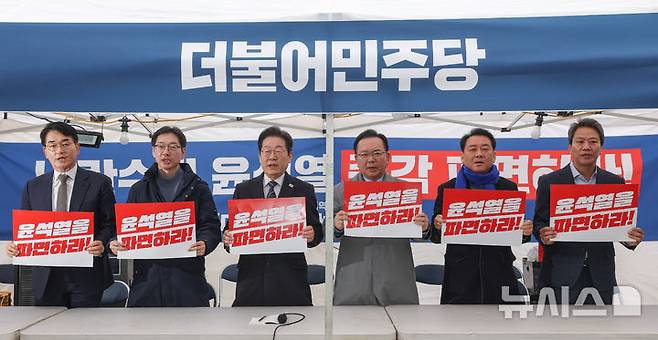 [서울=뉴시스] 황준선 기자 = 더불어민주당 박용진(왼쪽부터) 전 의원, 김경수 전 전남도사, 이재명 대표, 김부겸 전 국무총리, 이광재 전 국회사무총장, 임종석 전 대통령 비서실장이 12일 서울 종로구 경복궁 앞 더불어민주당 천막 농성장에서 열린 국난극복을 위한 시국간담회에서 피켓을 들고 구호를 외치고 있다. (공동취재) 2025.03.12. photo@newsis.com