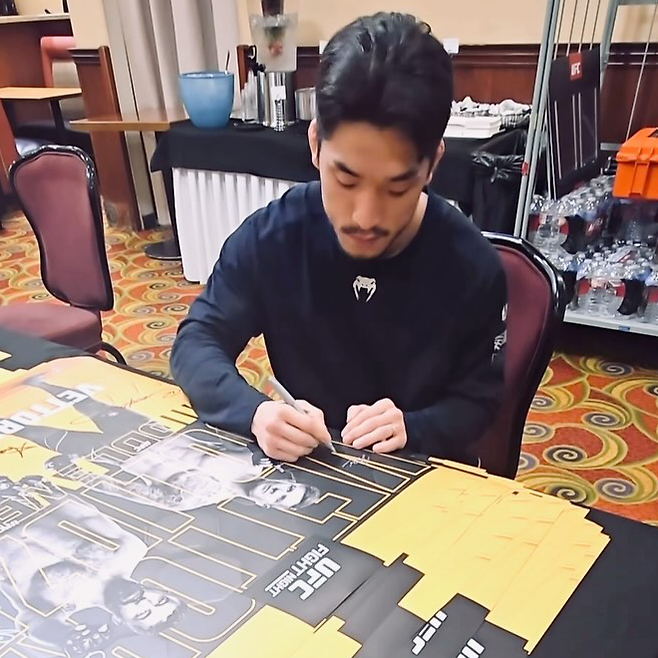 유수영이 2025년 3월 미국 네바다주 엔터프라이즈 UFC on ESPN+ 112 홍보용 포스터에 자필로 서명하고 있다. 사진@mma_kiho 영상 화면