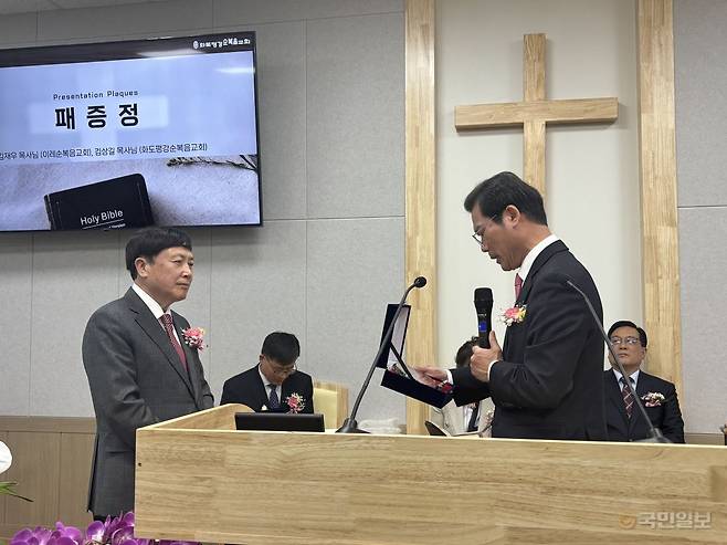 김상길(왼쪽) 화도평강순복음교회 목사가 16일 경기동북지방회장인 김재우 이레순복음교회 목사에게 취임패를 받고 있다.