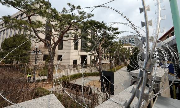 철조망으로 둘러싸인 헌재 - 윤석열 대통령 탄핵심판 선고를 앞둔 16일 서울 종로구 헌법재판소 담벼락에 원형 철조망이 설치돼 있다. 경찰은 선고 당일 ﻿헌재 뒤편 골목에 경찰 차량으로 1차 차벽을 마련하고, 헌재 내부 뒷마당에 펜스와 쇠사슬 자물쇠 등을 보강해 출입구를 막았다. 뉴스1