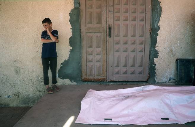 17일(현지시간) 가자지구 중부의 데이르 엘발라흐에 위치한 알악사 순교자 병원에서, 브레이지 수용소 동쪽에서 이스라엘 드론 공습으로 사망한 팔레스타인 남성의 시신 옆에 한 소년이 서 있다. (사진=AFP)