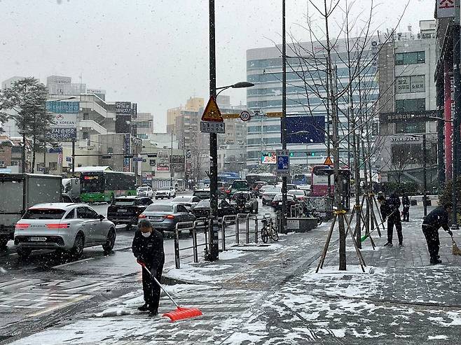 18일 오전 서울 마포구 홍대입구역 인근에서 작업자들이 보도 위에 쌓인 눈을 치우고 있다. /김정은 기자