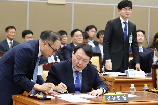 2019년 10월17일 윤석열 당시 검찰총장이 대검찰청에 대한 국회 국정감사에서 자료를 검토하고 있다. 왼쪽은 이원석 대검 기획조정부장(나중에 검찰총장 지냄), 오른쪽 서 있는 이는 한동훈 대검 반부패강력부장.강창광 선임기자 chang@hani.co.kr