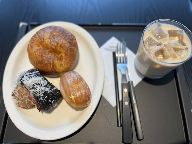 (Clockwise from top) A plain bagel, lemon madeleine and bacon pizza bread are served at Aufglet Seongsu in Seongdong-gu, eastern Seoul. (Park Jun-hee/The Korea Herald)