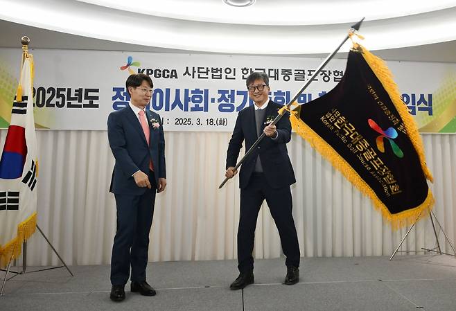 지난 18일 서울 송파구 올림픽파크텔에서 열린 한국대중골프장협회 협회장 이·취임식에서 임기주 전임 회장으로부터 협회기를 전달받은 우정석 신임회장(오른쪽)이 협회기를 흔들고 있다. 한국대중골프장협회