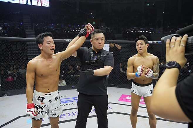 이정현(왼쪽)이 2025년 3월 서울특별시 장충체육관 제3대 로드FC 플라이급 챔피언 결정전 승리 선언을 받고 있다. 오른쪽은 고동혁. 사진=세계격투스포츠협회