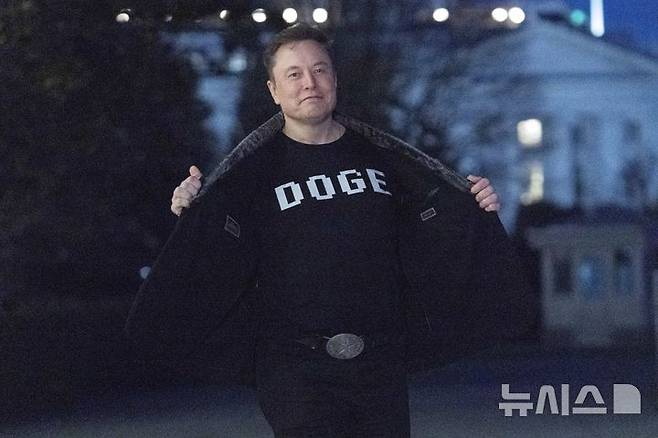 [워싱턴=AP/뉴시스]일론 머스크가 지난 9일(현지시각) 백악관에서 정부효율화부(DOGE)라는 글자가 크게 새겨진 티셔츠를 기자들에게 자랑하고 있다. 미 연방법원이 18일 머스크의 국제개발처(USAID) 폐쇄 주도가 헌법 위반이며 의회 권한 침해라며 머스크를 법정 모독으로 처벌할 수 있다고 경고하는 판결을 내렸다. 2025.3.19.