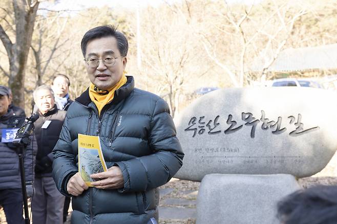 김동연 경기도지사가 지난달 13일 광주시 무등산 문빈정사 ‘노무현의 길’&nbsp;앞에서 노란 스카프를 두른 채 노무현 전 대통령 관련&nbsp;서적을 들고 기념촬영을 하고 있다. 경기도 제공