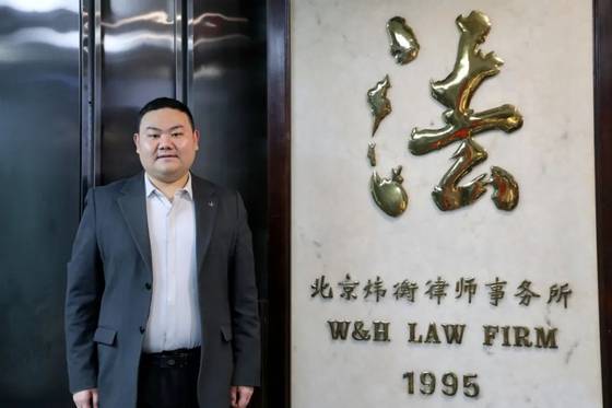 대학교 경비원으로 근무하다 변호사의 꿈을 이룬 류정이 자신이 근무하는 로펌 앞에서 기념사진을 촬영했다. 사진 중국 베이징대 위챗 계정 캡처