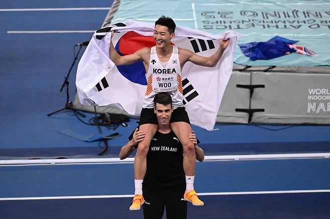 해미시 커가 21일 중국 난징 유스올림픽스포츠파크에서 열린 2025 세계실내선수권 남자 높이뛰기 결선이 끝난 뒤 우승한 우상혁을 목마태우고 있다.    난징 | AFP연합뉴스
