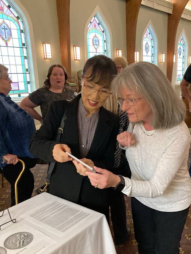 /스테이시 박 밀번 가족어머니 진 밀번씨가 15일 열린 시어머니의 장례식에서 영결식 손님에게 딸의 얼굴이 새겨진 동전에 대해 설명하고 있다.