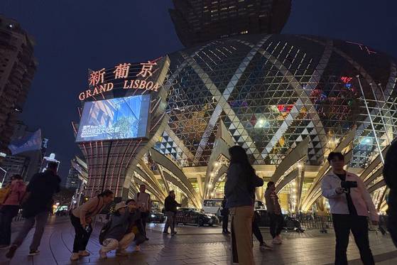 Tourists take photos outside the Grand Lisboa casino on Dec. 13, 2024. [AP/YONHAP]