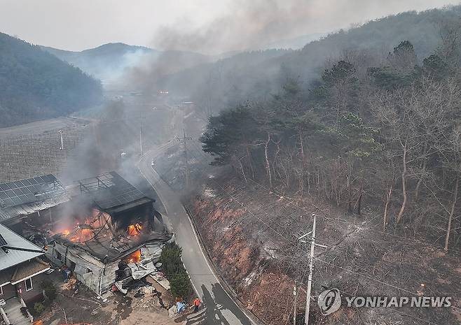 산불 번지는 의성 (의성=연합뉴스) 윤관식 기자 = 22일 경북 의성군 안평면 괴산리에서 발생한 산불이 급격하게 확산하는 가운데 한 주택 건물이 산불이 옮겨붙어 소실돼 있다. 2025.3.22 psik@yna.co.kr