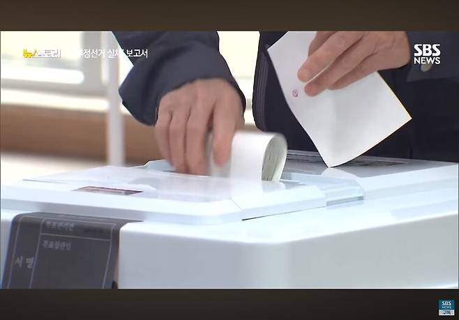 투표용지를 접지 않고 구부린 채 투표함에 넣는 유권자의 모습. ‘뉴스토리’ 갈무리