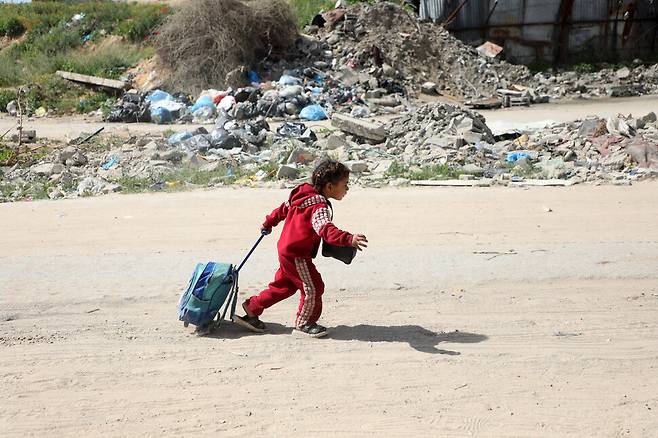 2025년 3월19일 팔레스타인 땅 가자지구 북부 가자시티 외곽에서 한 소녀가 짐 가방을 끌고 피란길에 오르고 있다. 신화 연합뉴스