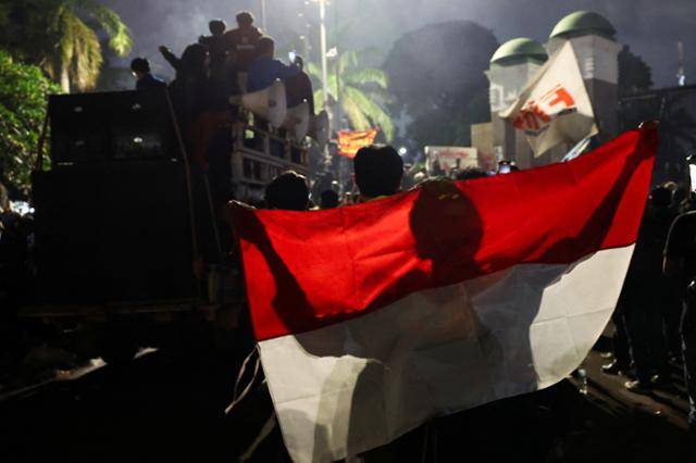 지난 20일 인도네시아 자카르타 의회 밖에서 군인의 겸직 범위를 확대하는 군법 개정안 반대 시위에 참여한 사람이 인도네시아 국기를 들고 있다. 자카르타=로이터 연합뉴스
