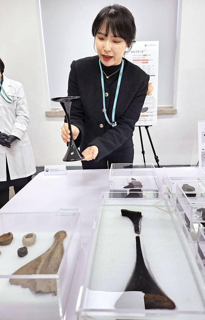 김해 봉황동 유적에서 출토된 옻칠 두형 그릇(오른쪽 아래). 사라진 윗접시 부분을 추정해 만든 복원품을 김지연 학예사가 보여주고 있다. /허윤희 기자